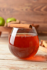 Tasty drink with cinnamon in glass on wooden background