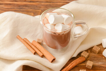 Fototapeta na wymiar Tasty cocoa with cinnamon and marshmallows in cup on wooden background
