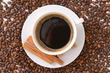 Tasty coffee with cinnamon in cup on beans