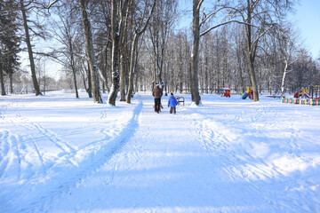 Fototapeta premium Winter old Park and people walking in it, in the background - a Playground-the concept of family walks in the fresh air