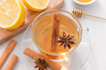 Tasty tea with cinnamon, honey and lemon in cup on light background