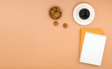 Banner with a notebook, notepad, coffee and cookies on a beige background. Template for posts with space for text.