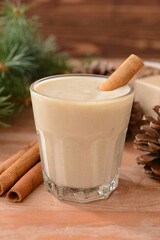 Tasty milkshake with cinnamon in glass on wooden background