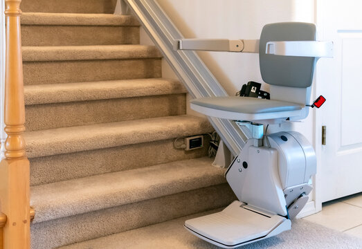 An electric, motorized chair life for persons with disabilities on a carpeted staircase in a residential home.