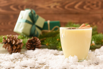 Tasty milkshake with cinnamon in glass on wooden background
