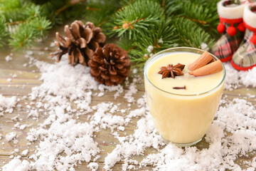 Tasty milkshake with cinnamon in glass on wooden background