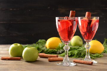 Tasty mulled wine with cinnamon in glasses on wooden background