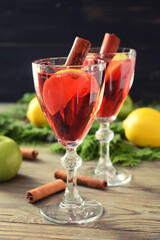Tasty mulled wine with cinnamon in glasses on wooden background