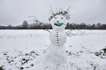 Funny snowman on snowy field wearing a medical face mask against coronavirus, Covid-19 
