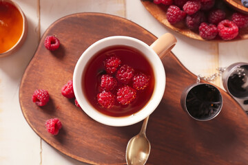 Cup of hot tea with raspberry on wooden background