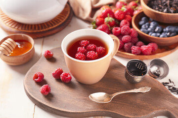Cup of hot tea with raspberry on wooden background