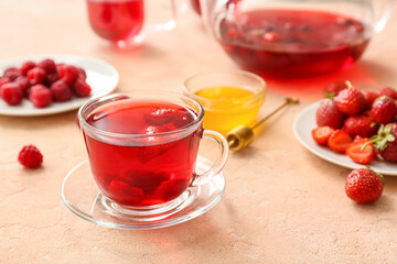 Cup of hot tea with berries on light background