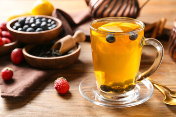 Cup of hot tea with lemon and blueberry on wooden background