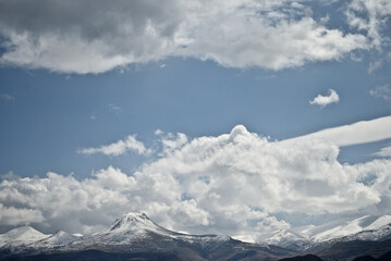 Fototapeta na wymiar Clouds have accumulated on beautiful snow-capped mountains