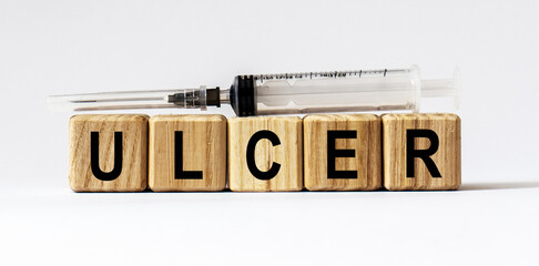 Text ULCER made from wooden cubes. White background