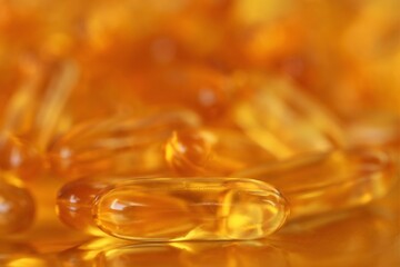 fish oil capsules close-up heap on blurred gold background.Fish oil in gelatin capsules. Omega three.Supplements for a healthy diet. Healthy fats