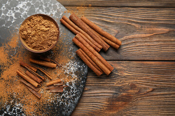 Cinnamon sticks and powder on wooden background