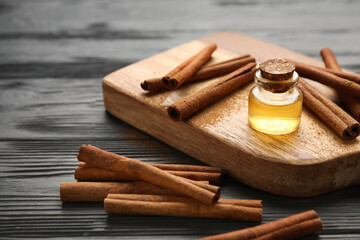 Cinnamon sticks and bottle of oil on wooden background