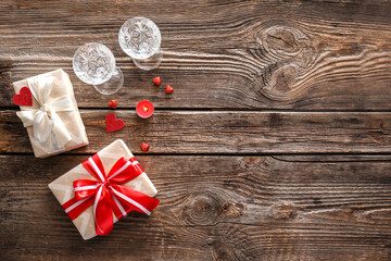 Gifts for Valentine's Day, glasses and candle on wooden background