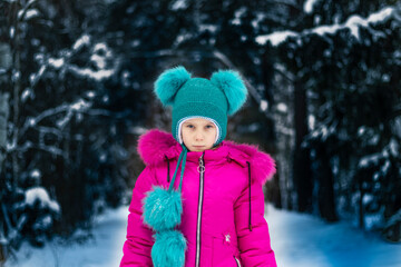 natural light. a girl in a red jacket and a green hat is surrounded by a lot of snow. He looks at us. Soft focus.