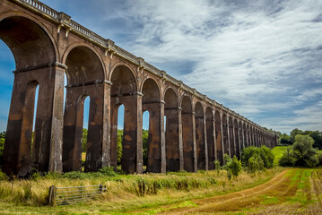 Obraz premium A view from a field down the length of the Ouse Valley viaduct in Sussex, UK on a summers day