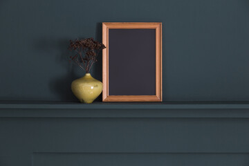 Vertical wooden photo frame mockup on dark paneled wall shelf.