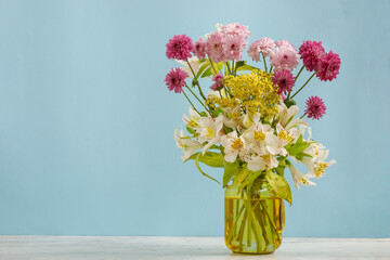 Florero amarillo con flores de diferentes tipos y colores sobre una mesa. Concepto decoración de interiores