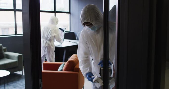 Cleaners wearing protective clothes sanitizing modern office space