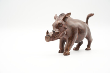 Brown warthog (Warzenschwein) made of wood, isolated on a white background. The real pig (Suidae) has its home in Africa. Copy space. Side View.