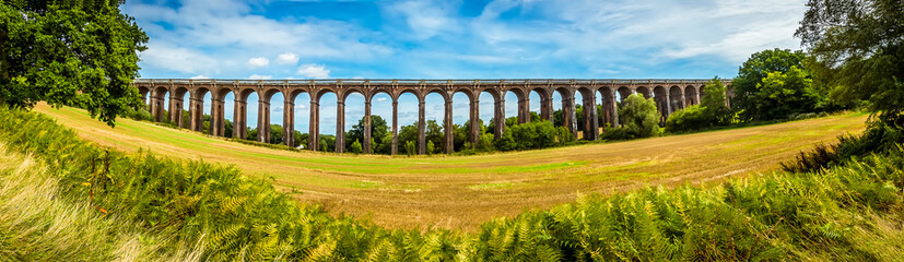 Fototapeta premium A wide-angle view over the hedgerows towards the Ouse Valley viaduct in Sussex, UK on a summers day