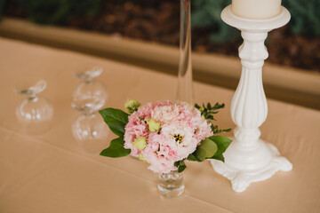 Coziness and style. Modern event design. Table setting at wedding reception. Floral compositions with beautiful flowers and greenery, candles, laying and plates on decorated table.