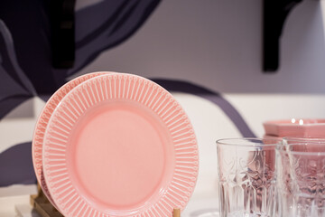 Commercial pink and white plates and bowls stacked with crystal wine glasses.Colorful ceramic clean dishware.Ceramic crockery tableware