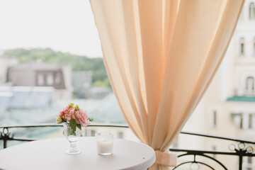 Coziness and style. Modern event design. Table setting at wedding reception. Floral compositions with beautiful flowers and greenery, candles, laying and plates on decorated table.