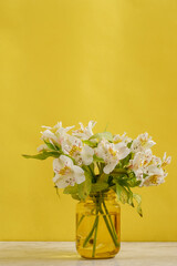 Florero amarillo con ramo de flores blancas sobre una mesa de mármol y fondo de color amarillo. concepto decoración de interiores