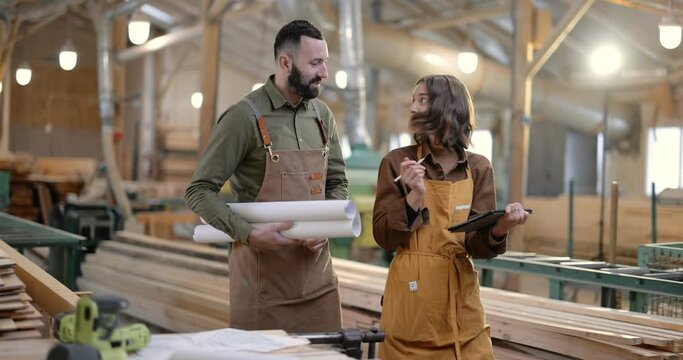 Carpentry workers discuss some working moments, walking through the manufacturing. Teamwork, creative work, designing woodwork at the joinery