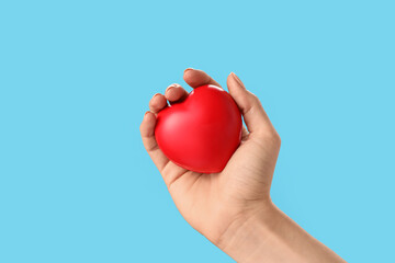 Hand with red heart on color background