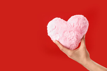 Hand with fluffy heart on color background