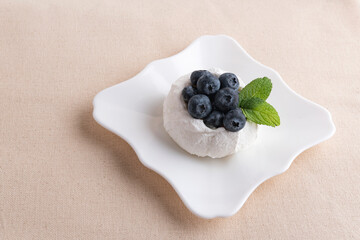 Meringue cake with fresh blueberries on saucer. Airy berry dessert. Top view