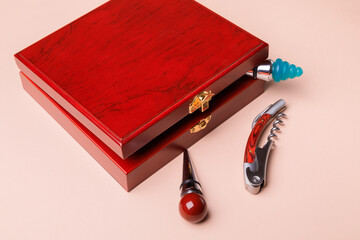 Gift set of corkscrew and removable lids. Wine corks and bottle openers in a wooden box on a pink...