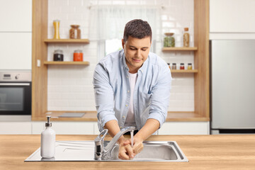 Man washing hands in a kitchen sink