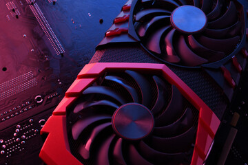 Computer game graphics card, videocard with two coolers on circuit board ,motherboard background. Close-up. With red-blue lighting