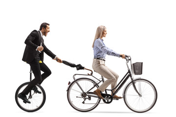 Man in a suit and tie holding an umbrella and riding a tricycle behind a woman on a bicycle © Ljupco Smokovski