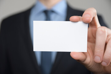 Businessman ,Business Man's hand hold showing business card - close up shot on grey background. Show a blank piece of paper. Paper visit card