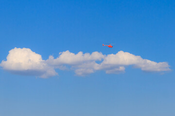 Flying orange helicopter in blue sky