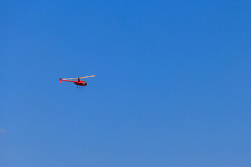 Fototapeta na wymiar Flying orange helicopter in blue sky