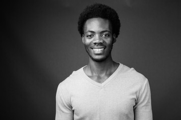 Young handsome African man against gray background