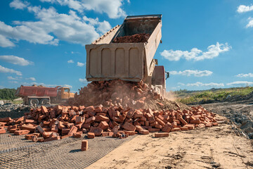 truck unloads old brick on a road under construction to a new construction site