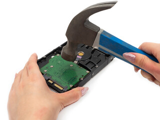 A woman's hand with a hammer smashes an old hard drive. The concept of anonymity and computer...