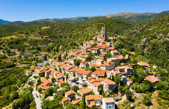General summer view of picturesque French village of Eus in natural region of Conflent with tightly grouped houses, medieval church and castle ruins on top of hill