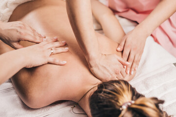 Obraz na płótnie Canvas Four hands of two masseurs on the patient back - synchronous massage